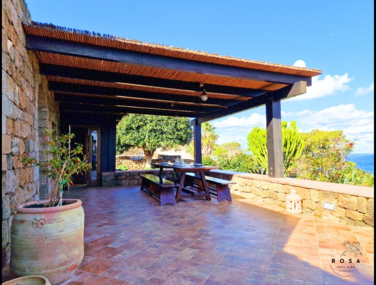 Terrazza privata con veranda coperta e zona pranzo del dammuso La Rosa dell’Alba, con vista mare